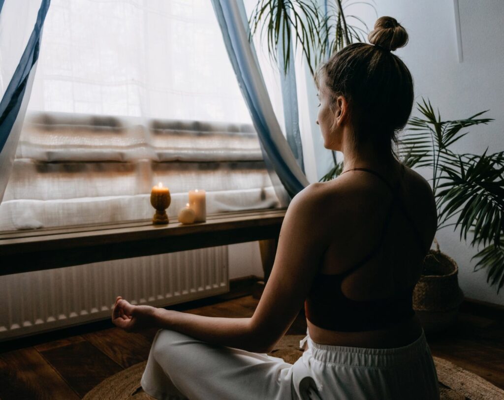 Une femme pratique la méditation vipassana devant une fenêtre