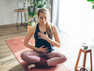 La cohérence cardiaque est une technique de respiration illustrée sur cette photo par une jeune femme sur un tapis en train de respirer calmement