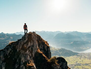 Personne debout au sommet d'une montagne contemplant un vaste paysage naturel, symbolisant la congruence, l'accomplissement personnel, la sérénité et l'harmonie intérieure.