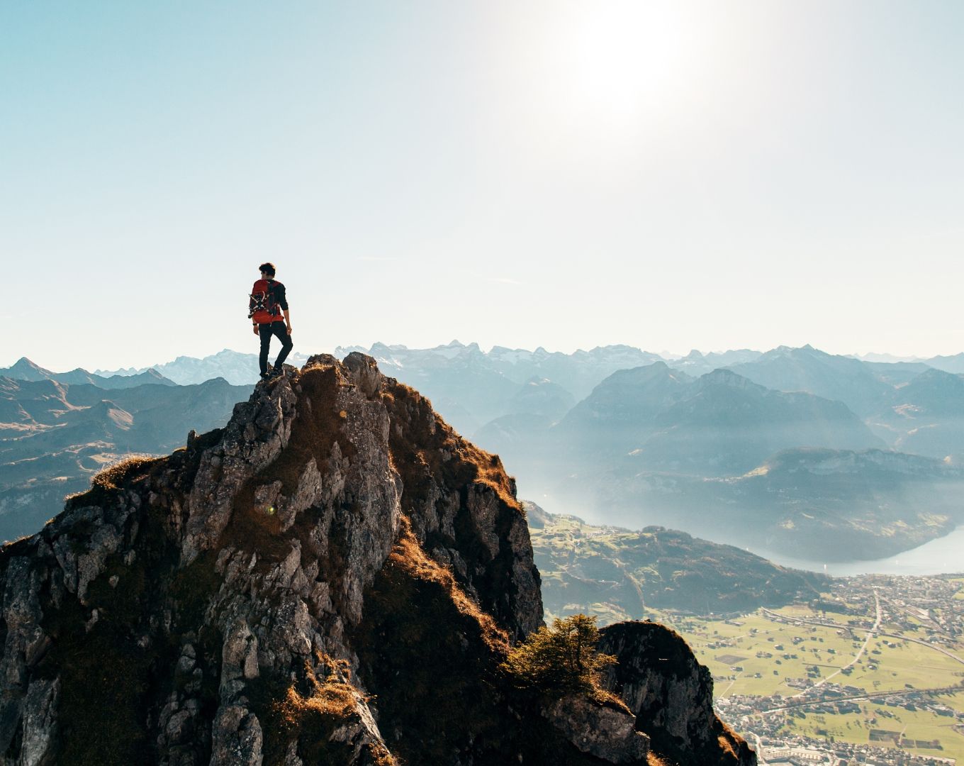 Personne debout au sommet d'une montagne contemplant un vaste paysage naturel, symbolisant la congruence, l'accomplissement personnel, la sérénité et l'harmonie intérieure.