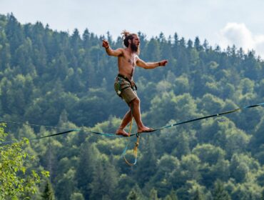 Un équilibriste sur un fil tendu dans la nature, symbolisant la peur de l'échec et l'équilibre entre risque et réussite.