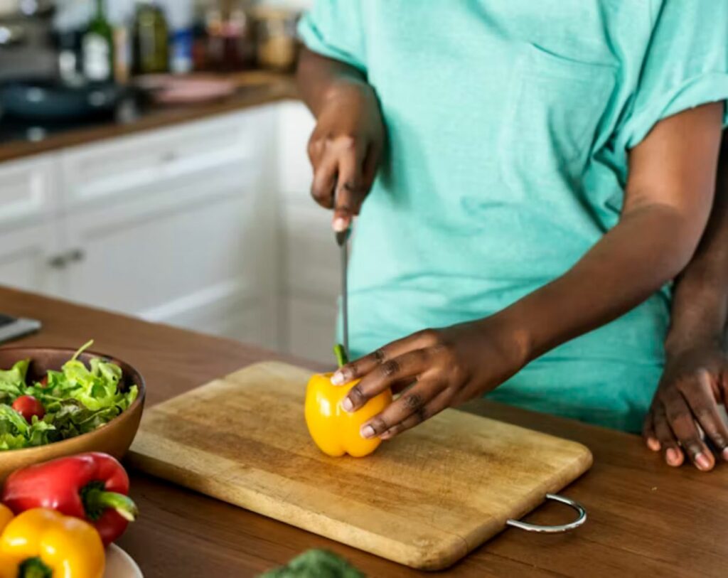 Homme coupant des poivrons en cuisine, illustrant le langage de l’amour par les services rendus.