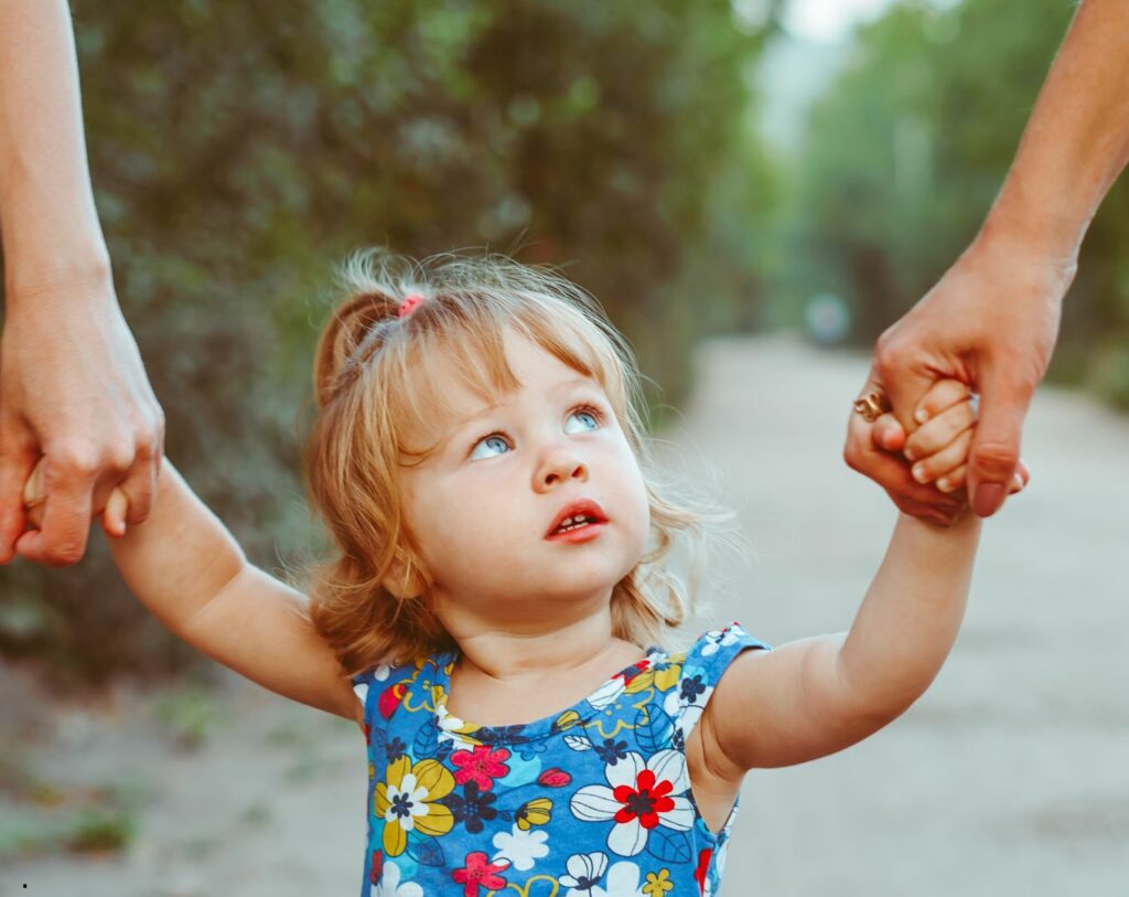 Une petite fille donne la main à ses parents, représentant l'amour inconditionnel qu'ils ressentent pour elle