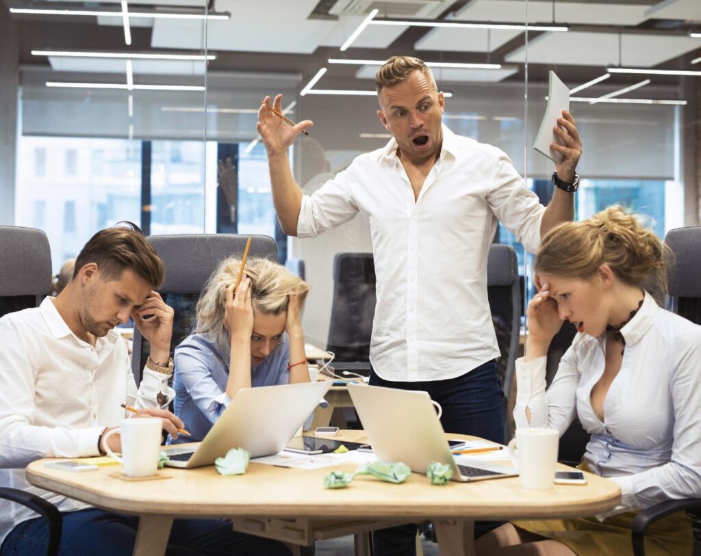 Manager s’énervant sur son équipe, illustrant le concept de projeter ses peurs sur les autres, ici sa propre peur de ne pas atteindre les attentes.