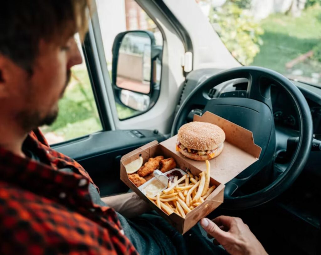 Personne introvertie mangeant un burger dans sa voiture, illustrant le lien entre fast food à emporter et le MBTI.