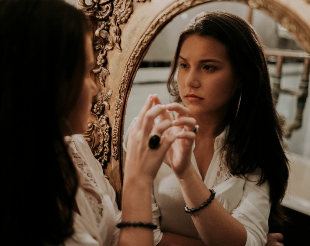 Une personne regardant dans un miroir avec un reflet inquiétant, symbolisant l'acte de projeter ses peurs sur l'autre.