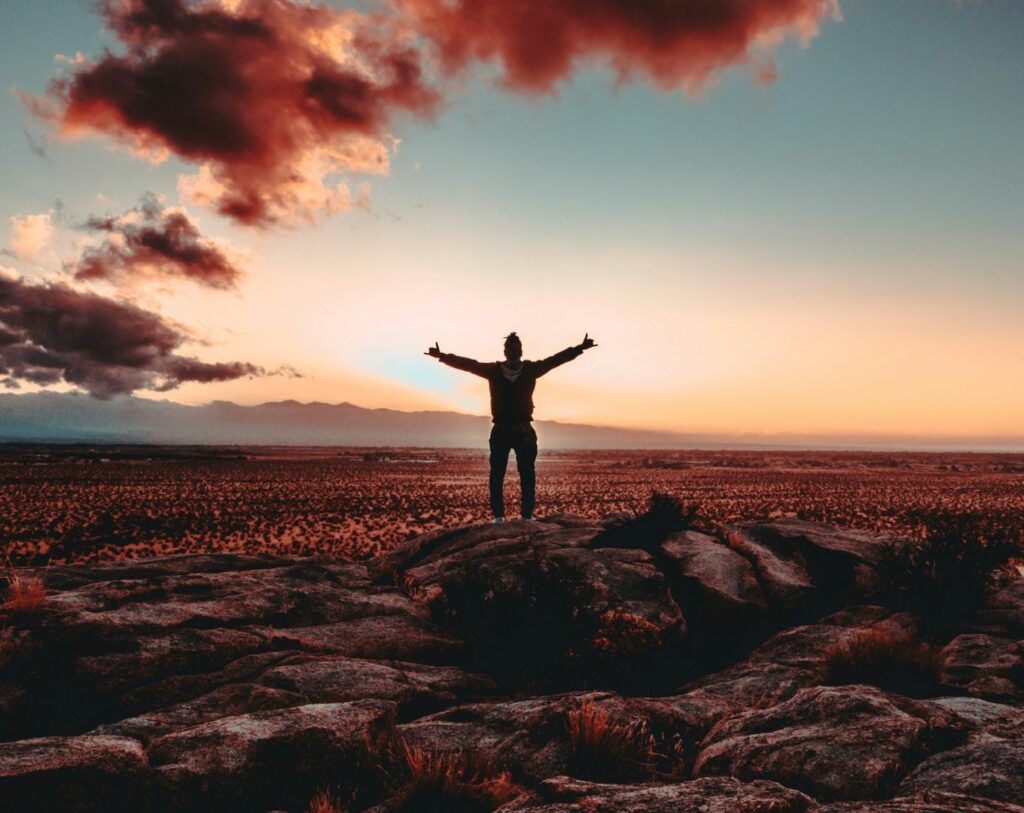 La méthode des petits pas ou Kaizen te mène vers l'atteinte de tes objectifs. Sur cette image, un homme savoire l'atteinte de ses objectifs face à un magnifique paysage.