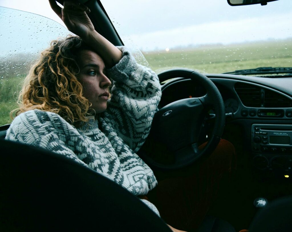 Une femme qui est entrain de penser trop dans sa voiture, représentant l'overthinking.