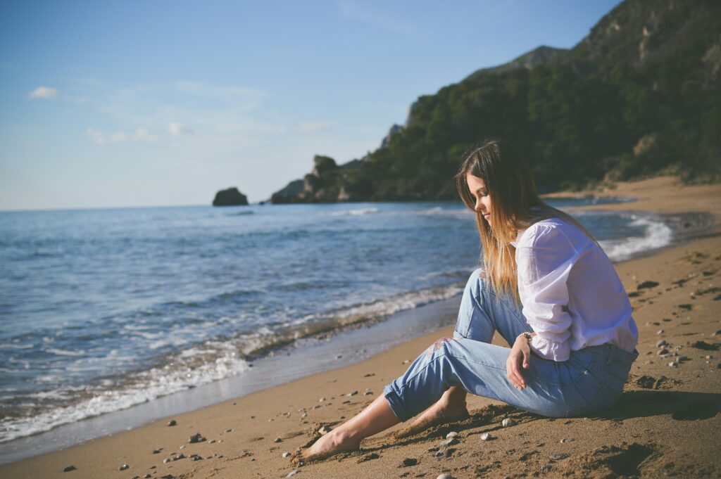 Femme seule et triste sur la plage, illustrant les effets des violences psychologiques